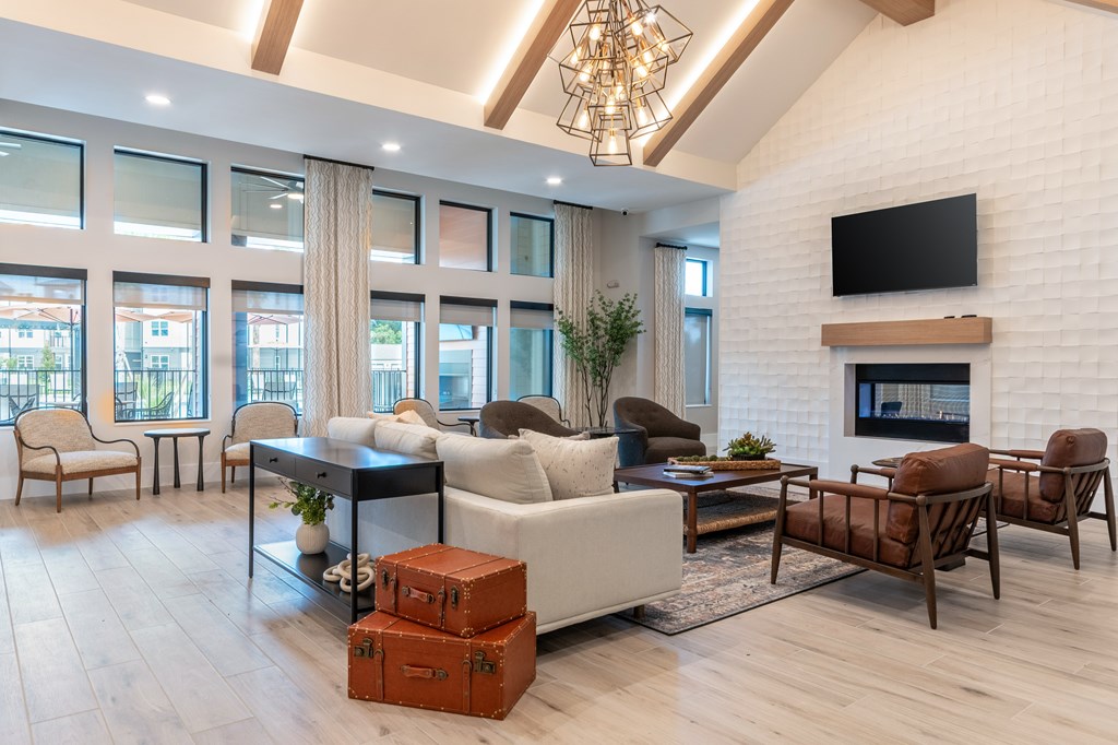 A clubhouse with a white couch, a black coffee table, and a fireplace with a flat screen TV above it at SW 38th Avenue Apartments in Ocala, FL.