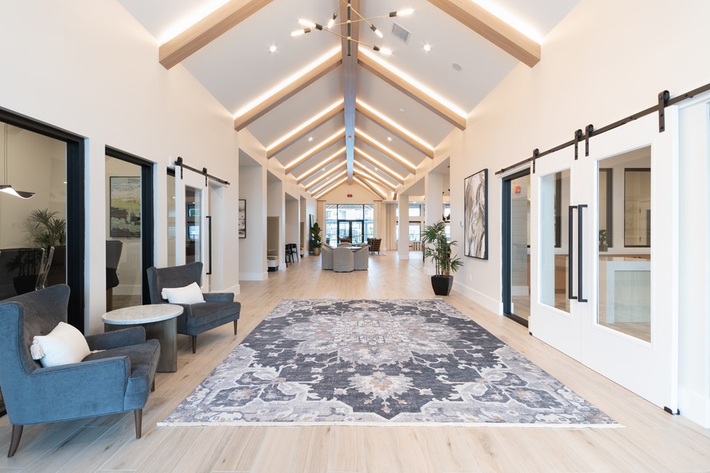 A long hallway with a rug in the middle and chairs on the left at SW 38th Avenue Apartments in Ocala, FL.