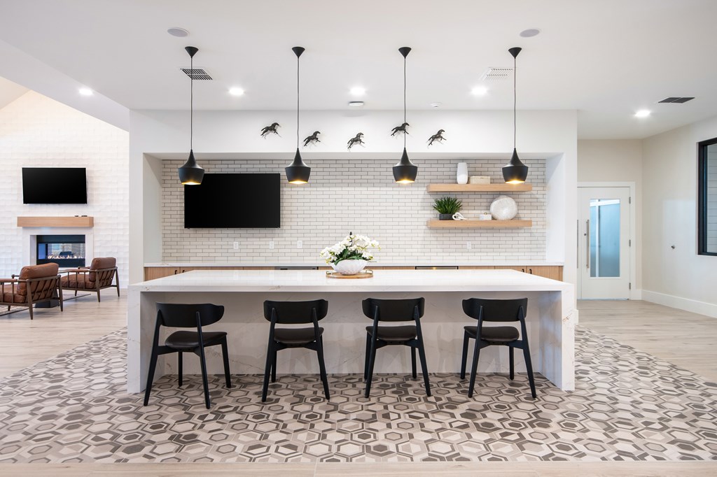 A modern kitchen with a white brick wall and a long white island.