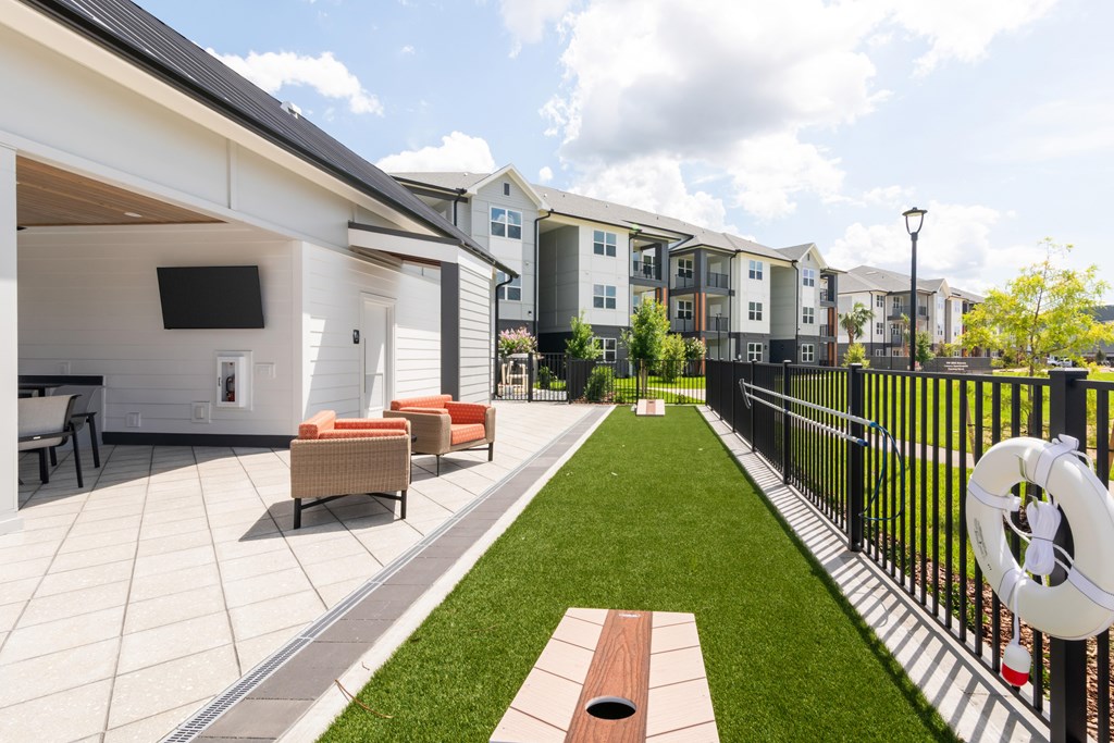 A patio with a white couch and a black fence.