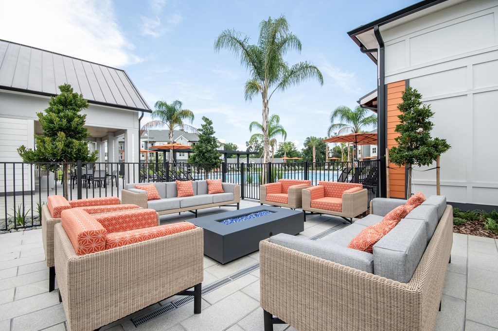 A patio with two chairs and a table with orange cushions.