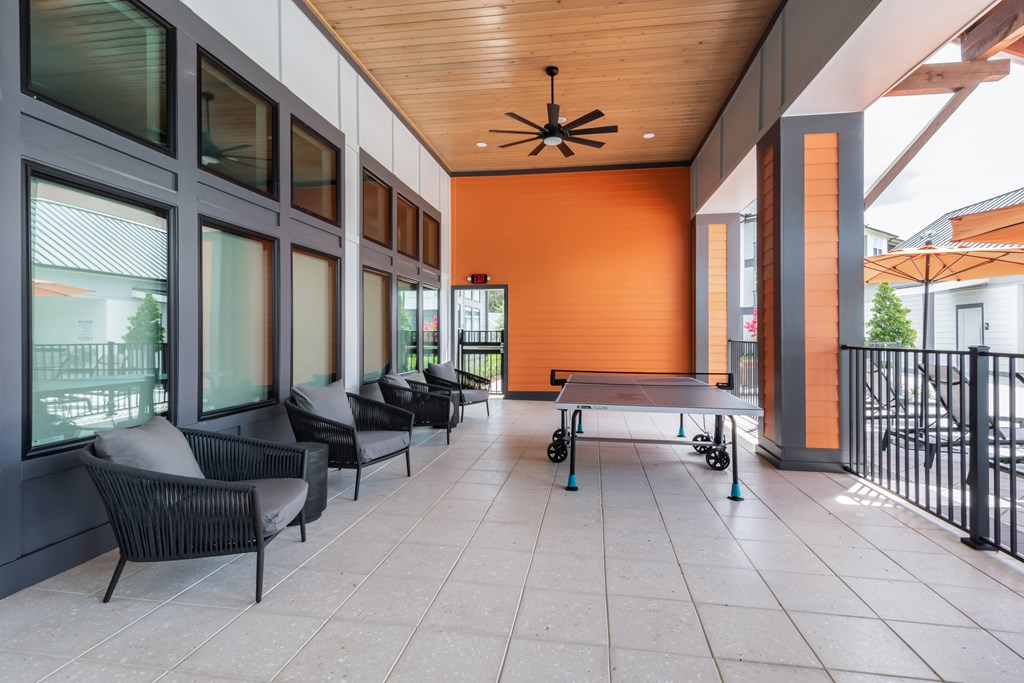 A patio with a table and chairs and a ping pong table.