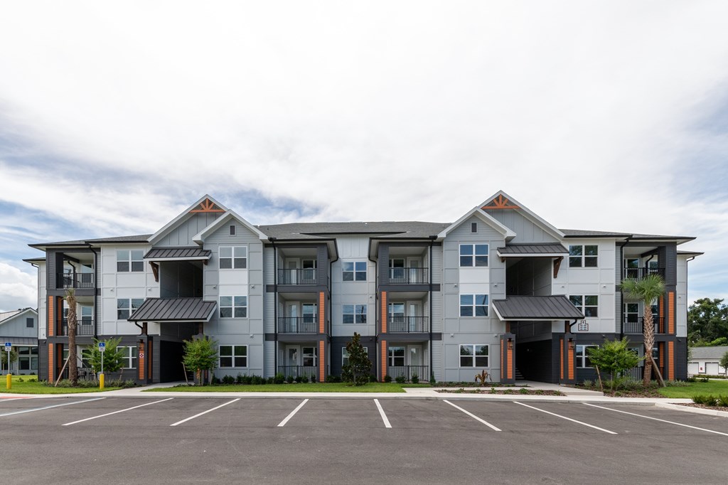 A large apartment building with a parking lot in front.