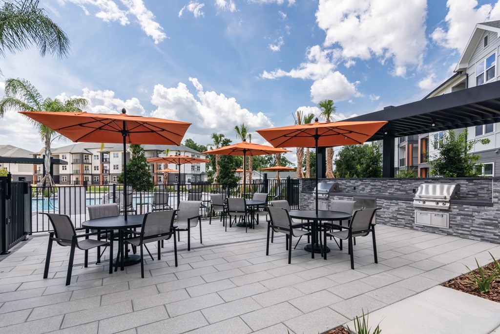 A patio with tables and chairs under orange umbrellas.