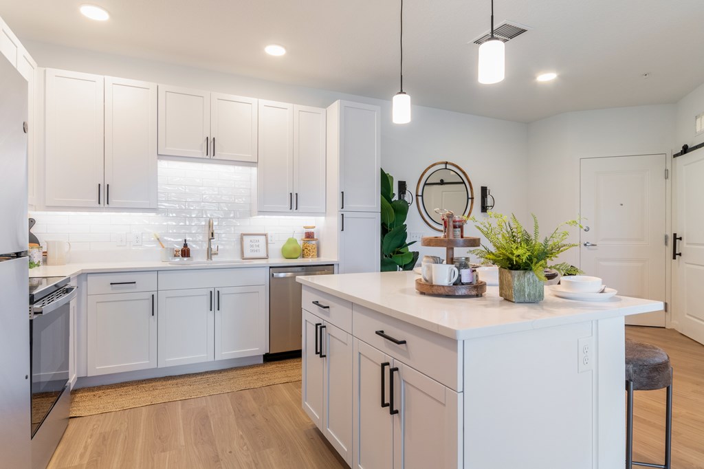 A modern kitchen with white cabinets and a wooden floor.