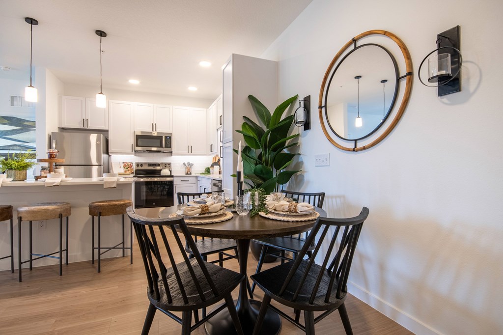A modern dining room with a round mirror and a dining table with chairs.