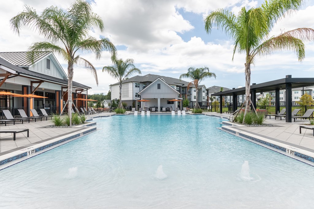 A large swimming pool surrounded by palm trees and lounge chairs at SW 38th Avenue Apartments in Ocala, FL