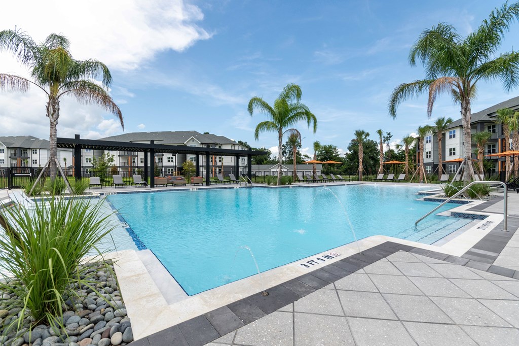 A swimming pool surrounded by palm trees and a building in the background.