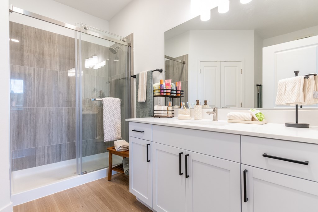 A bathroom with a white counter and a glass shower.