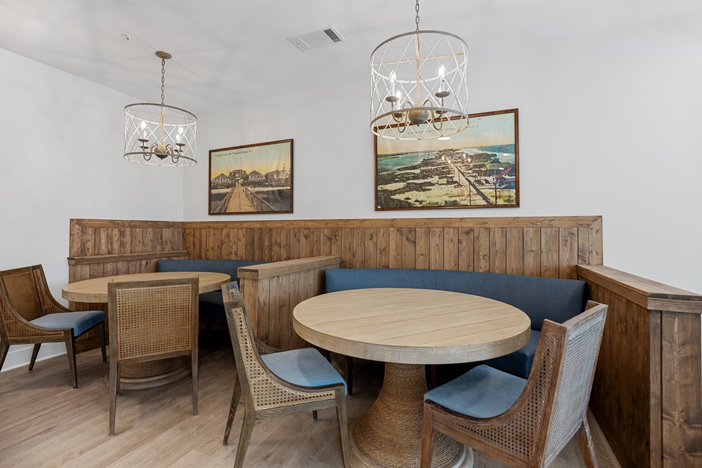 Clubhouse Eating and Sitting Area with Wooden Tables Surrounded by Chairs and Pictures on the Wall.