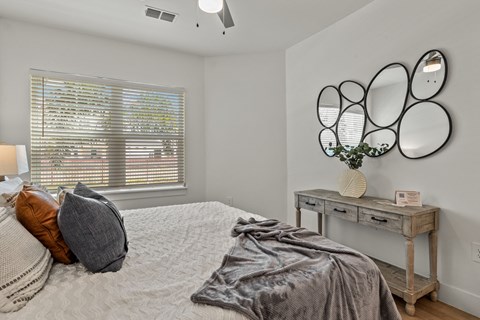 a bedroom with a bed and two mirrors on the wall