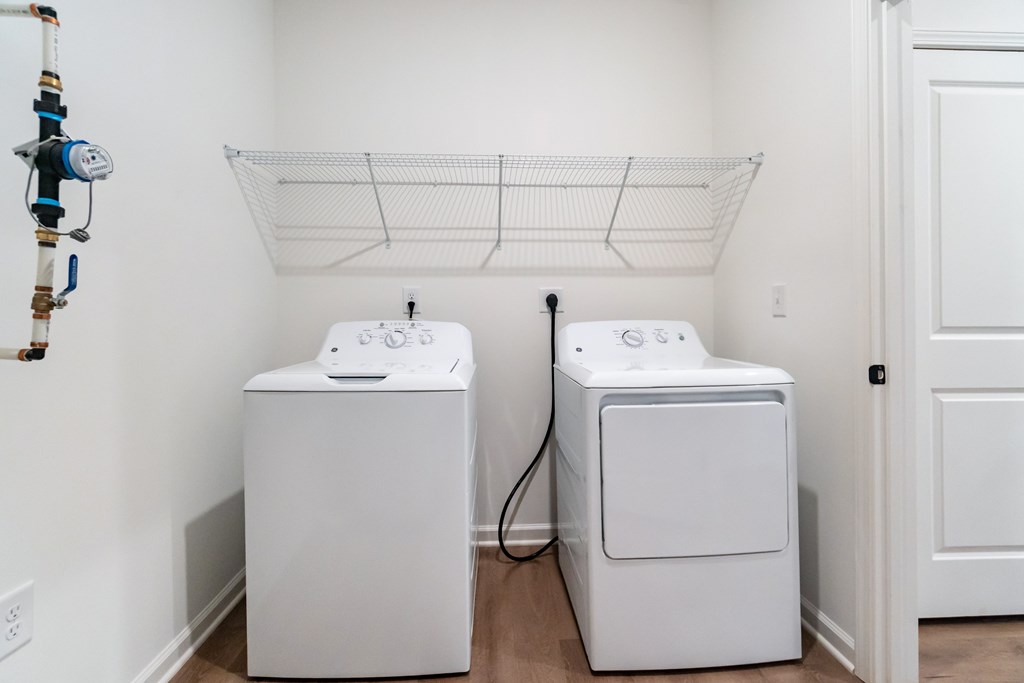A white wall with a washer and dryer in front of it at Evolve Lake Norman apartments in Mooresville, NC