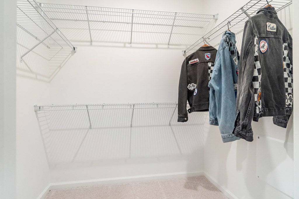 A row of jackets hang on a wire rack in a closet at Evolve Lake Norman apartments in Mooresville, NC