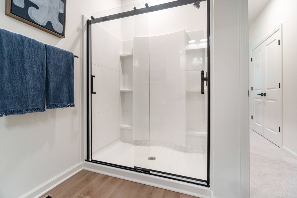 A bathroom with a glass shower door and a towel hanging on the wall at Evolve Lake Norman apartments in Mooresville, NC