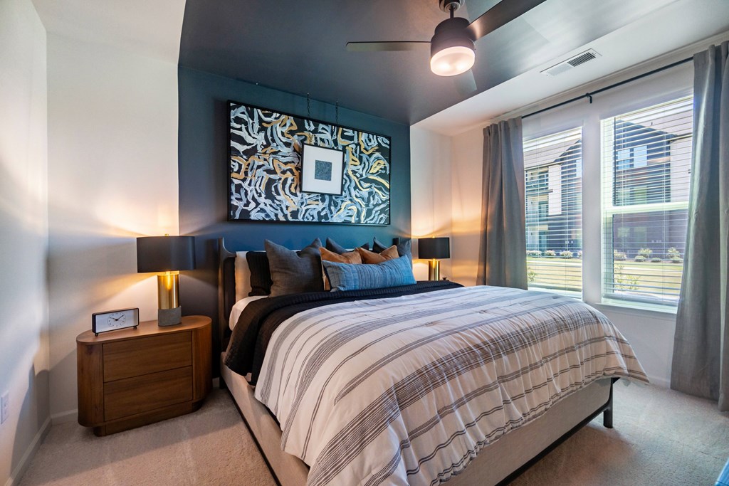 A bedroom with a bed, nightstand, and a large art at Evolve Lake Norman apartments in Mooresville, NCwork on the wall.