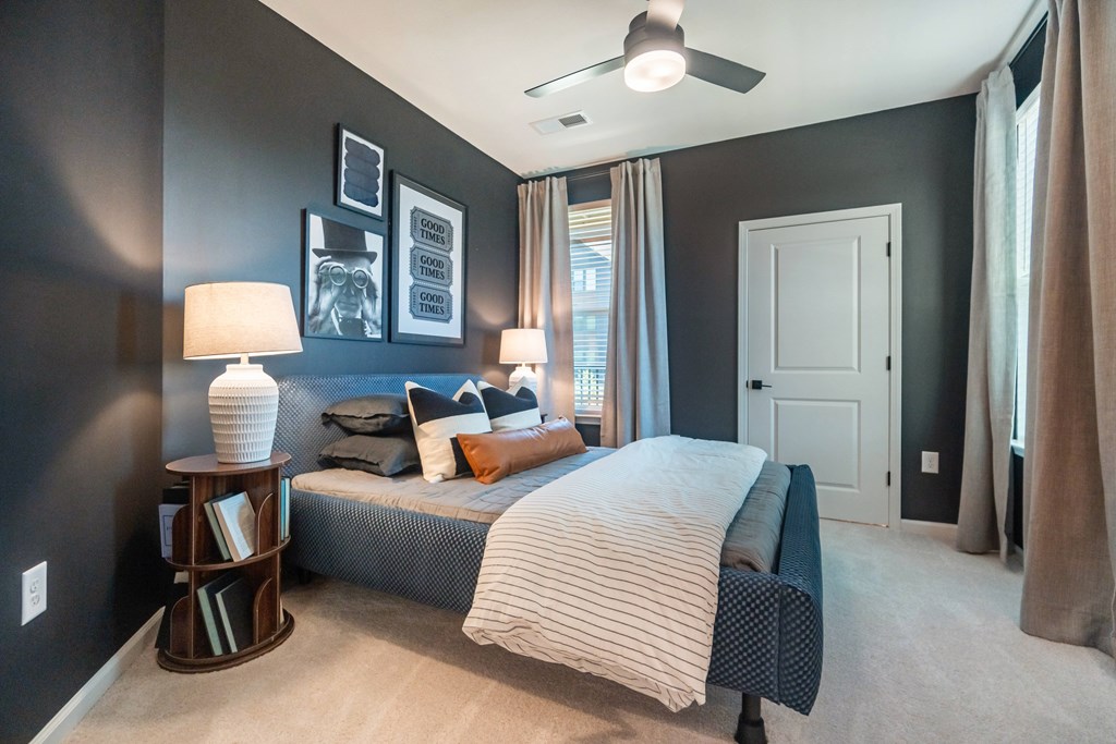 A bedroom with a bed, nightstand, and pictures on the wall at Evolve Lake Norman apartments in Mooresville, NC