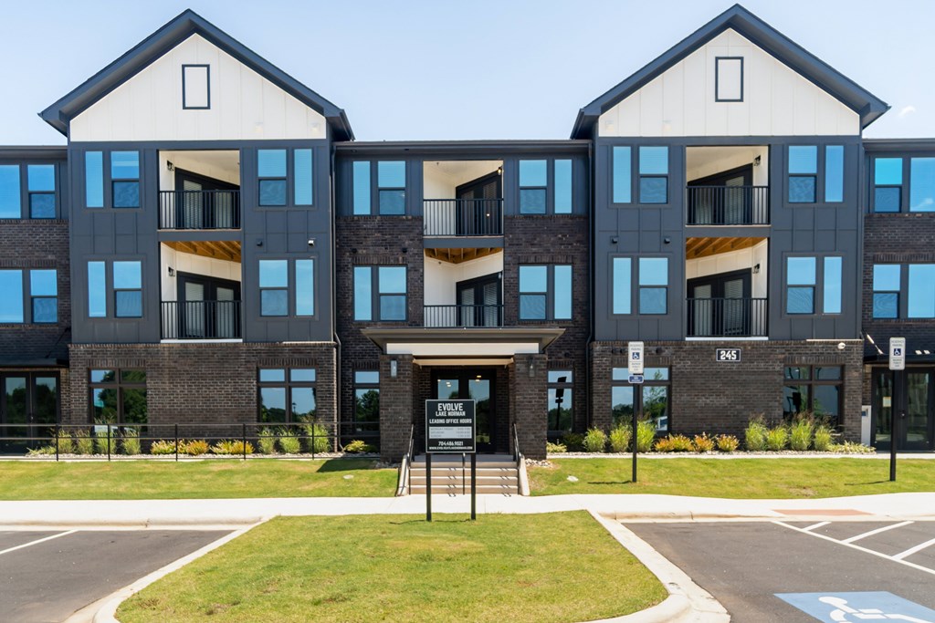 A modern building with a black and white facade and a sign in front at Evolve Lake Norman apartments in Mooresville, NC