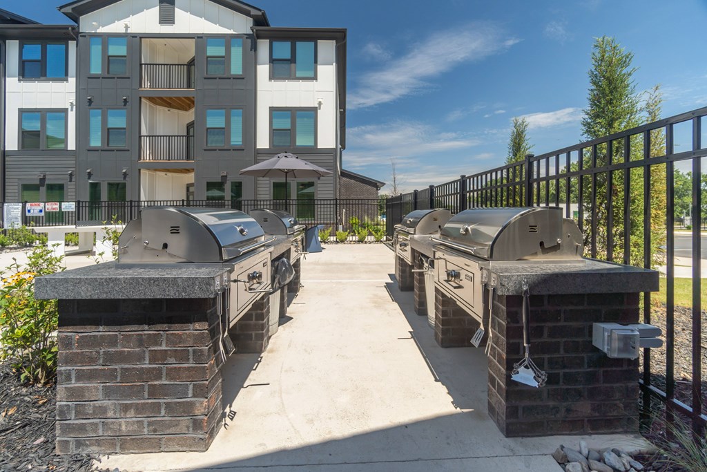 A sunny day at a residential building with a brick BBQ area in front at Evolve Lake Norman apartments in Mooresville, NC