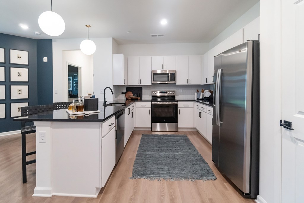 A modern kitchen with a black countertop and stainless steel appliances at Evolve Lake Norman apartments in Mooresville, NC