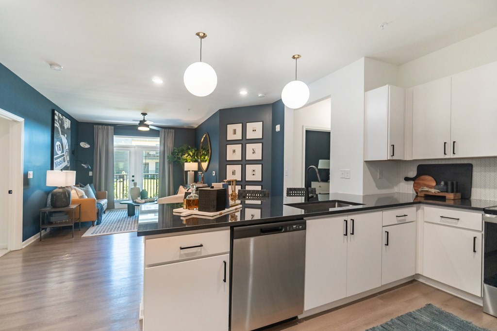 A modern kitchen with white cabinets and a black countertop at Evolve Lake Norman apartments in Mooresville, NC