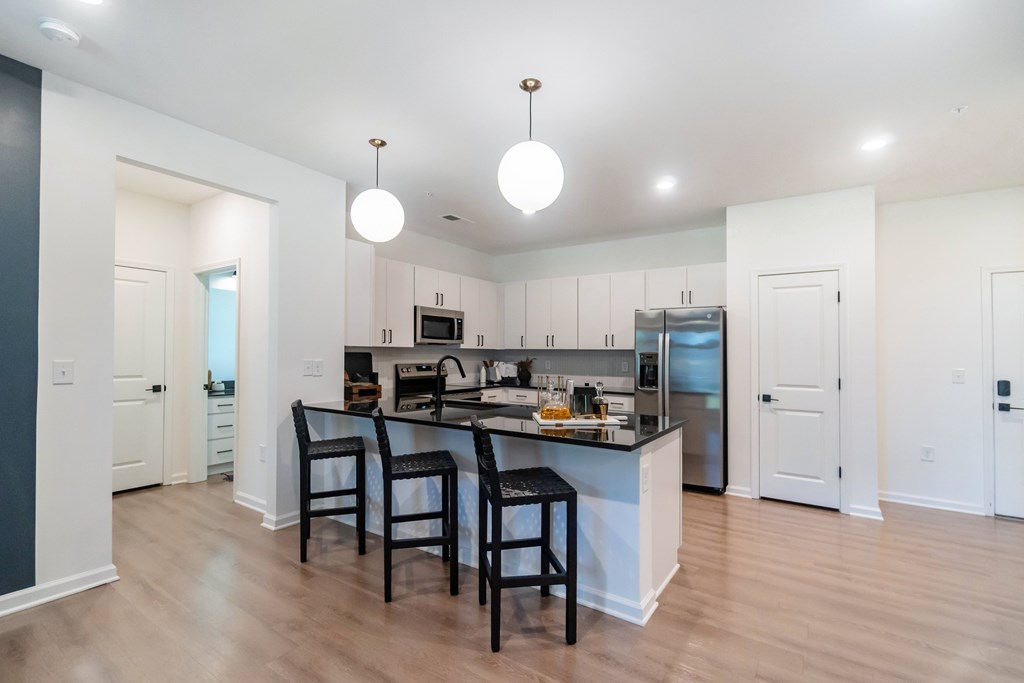 A kitchen with a bar and chairs at Evolve Lake Norman apartments in Mooresville, NC