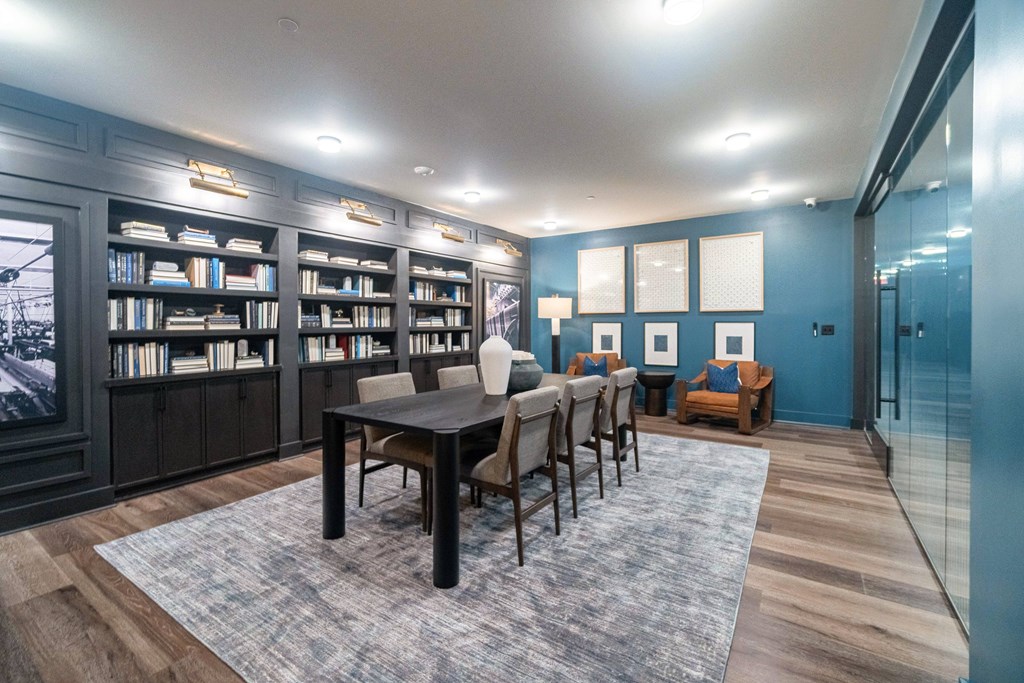A room with a long table surrounded by chairs and a bookshelf at Evolve Lake Norman apartments in Mooresville, NC
