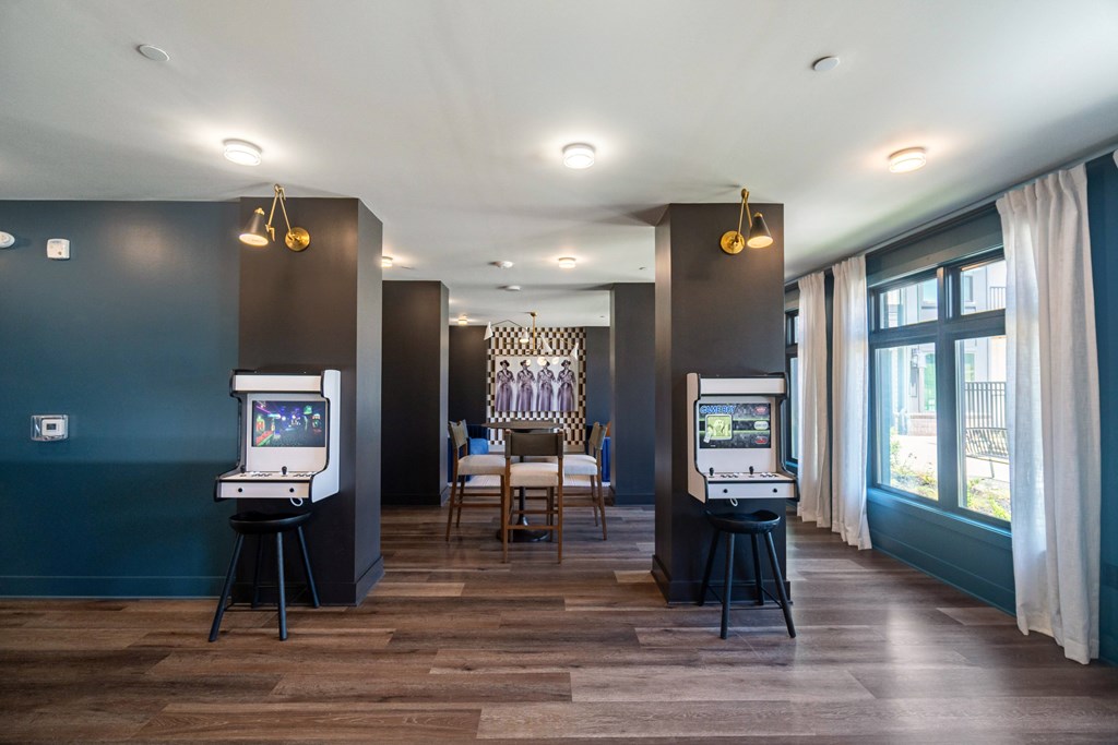 A room with two arcade machines and a dining table at Evolve Lake Norman apartments in Mooresville, NC.