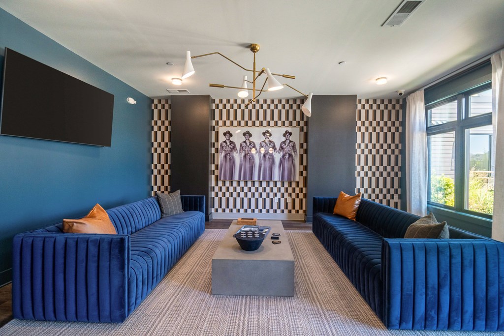 A living room with blue couches and a checkered wallpaper at Evolve Lake Norman apartments in Mooresville, NC