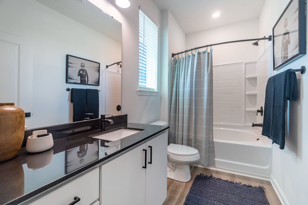 A bathroom with a black counter top and white walls at Evolve Lake Norman apartments in Mooresville, NC