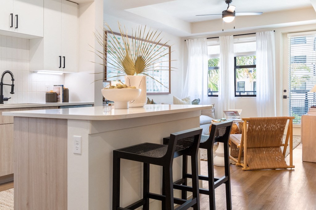 the kitchen and dining area of a house with a white counter and stools