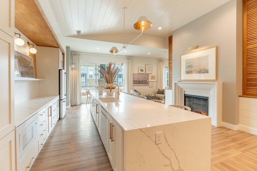 a large white kitchen with a fireplace and a marble counter top