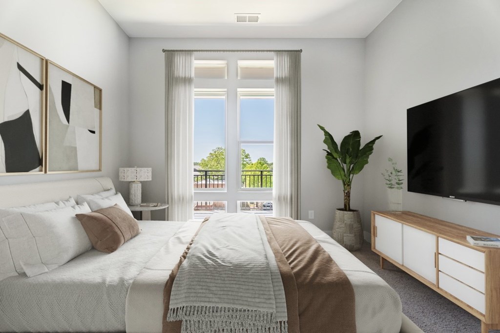 A bedroom with a large bed, a television, and a window with a view of the outside.