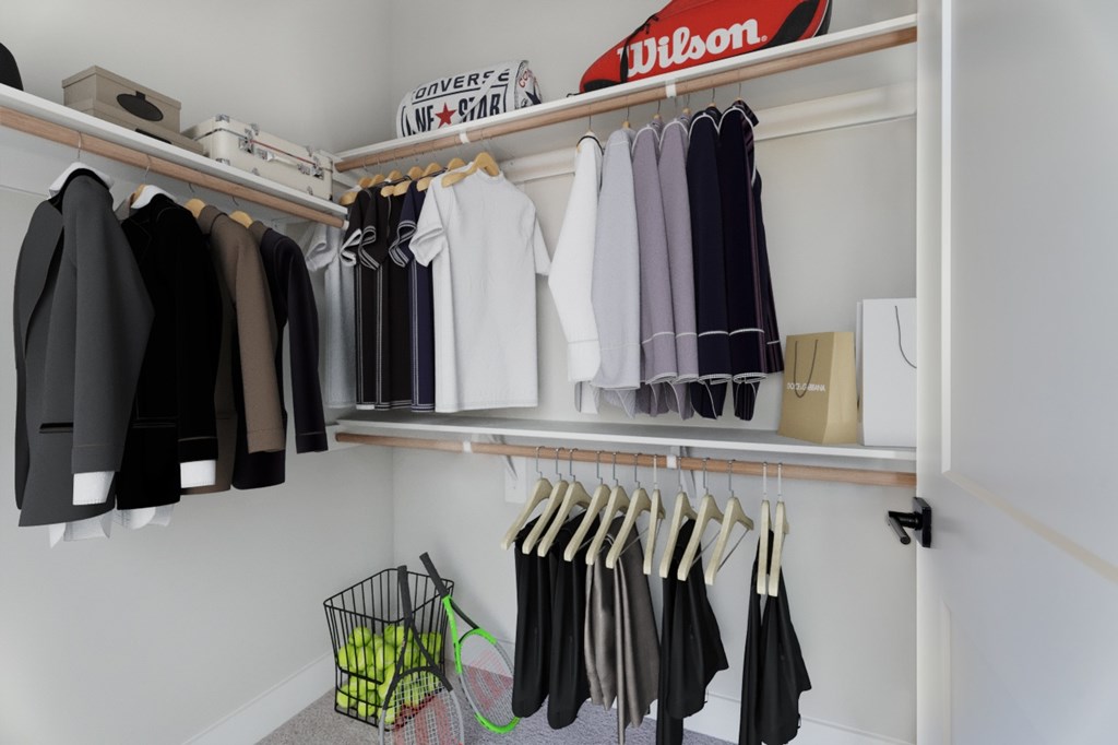 A closet with clothes hanging and a basket on the floor.