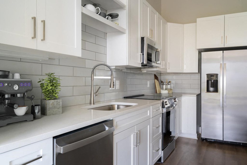 A modern kitchen with white cabinets and stainless steel appliances.