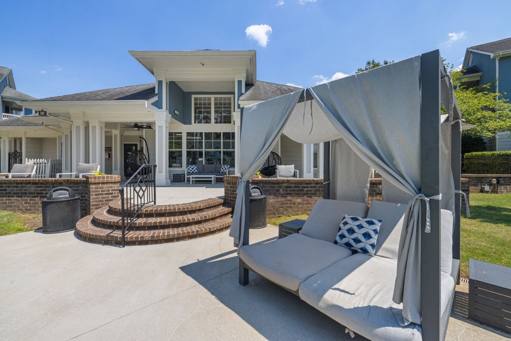 a patio with a couch and umbrellas in front of a house