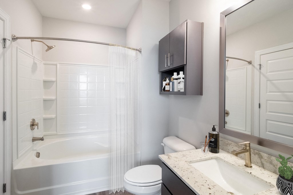 a bathroom with a white bathtub and a white toilet next to a sink with a mirror