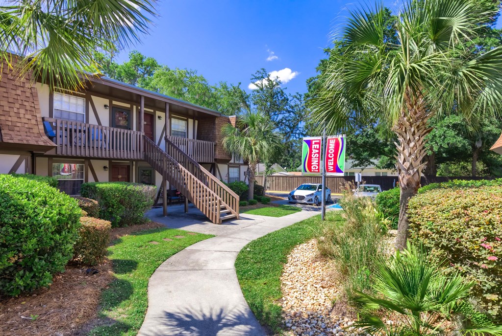 a sidewalk in front of a building with palm trees