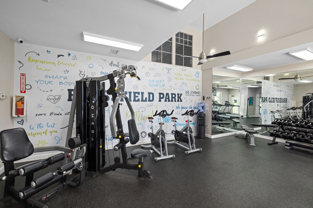 a gym with weights and a white wall with writing on it