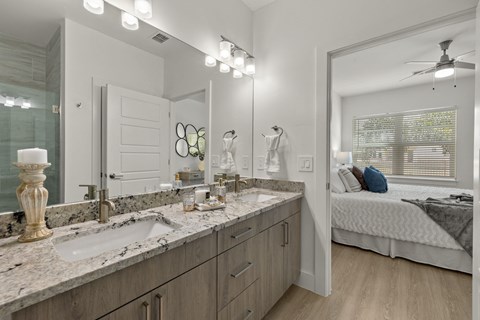 a bathroom with a sink and a mirror and a bedroom with a bed