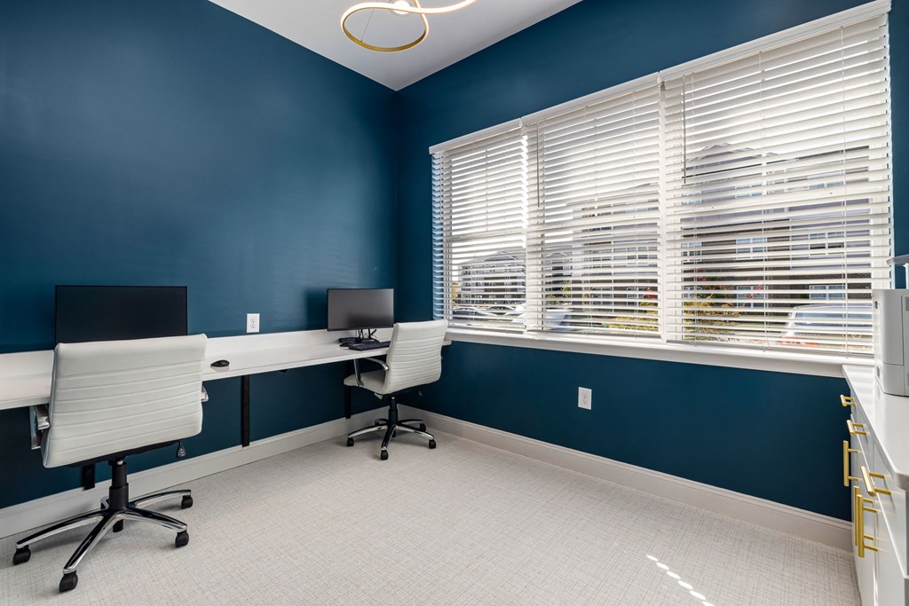 a office with two desks and two chairs and a window