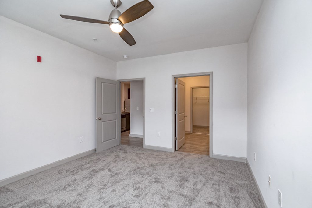 an empty living room with a ceiling fan and white walls