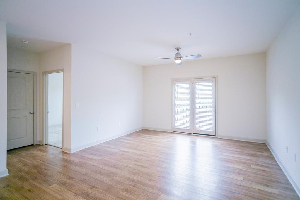 an empty living room with wood floors and a ceiling fan
