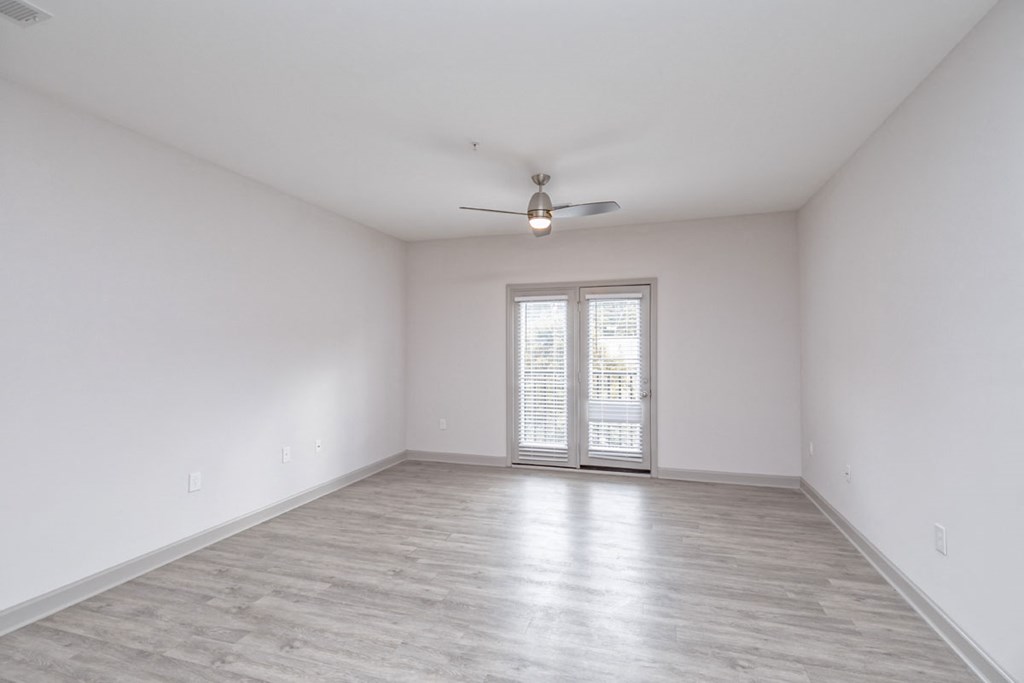 an empty living room with white walls and a ceiling fan