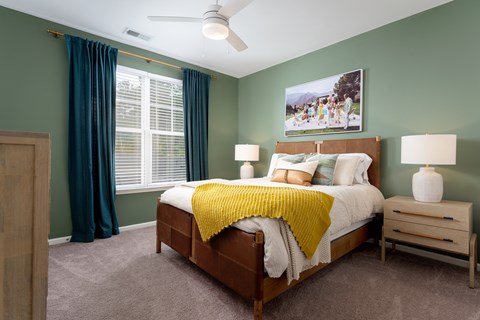 A bedroom with a bed, nightstand, and a ceiling fan at Evolve Holly Ridge Apartments in Holly Ridge, NC.