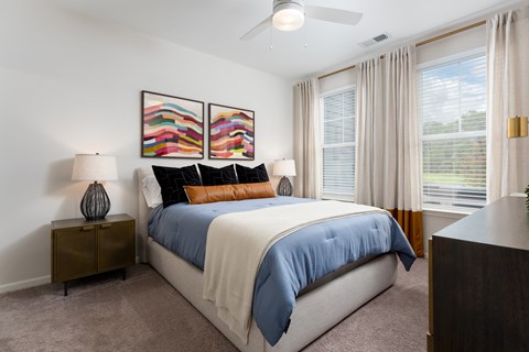 A bedroom with a large bed and two lamps at Evolve Holly Ridge Apartments in Holly Ridge, NC.