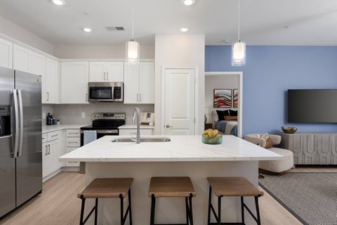 A modern kitchen with a large island and stools at Evolve Holly Ridge Apartments in Holly Ridge, NC.