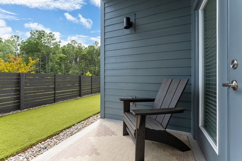 A black bench sits on a porch next to a blue door at Evolve Holly Ridge Apartments in Holly Ridge, NC.