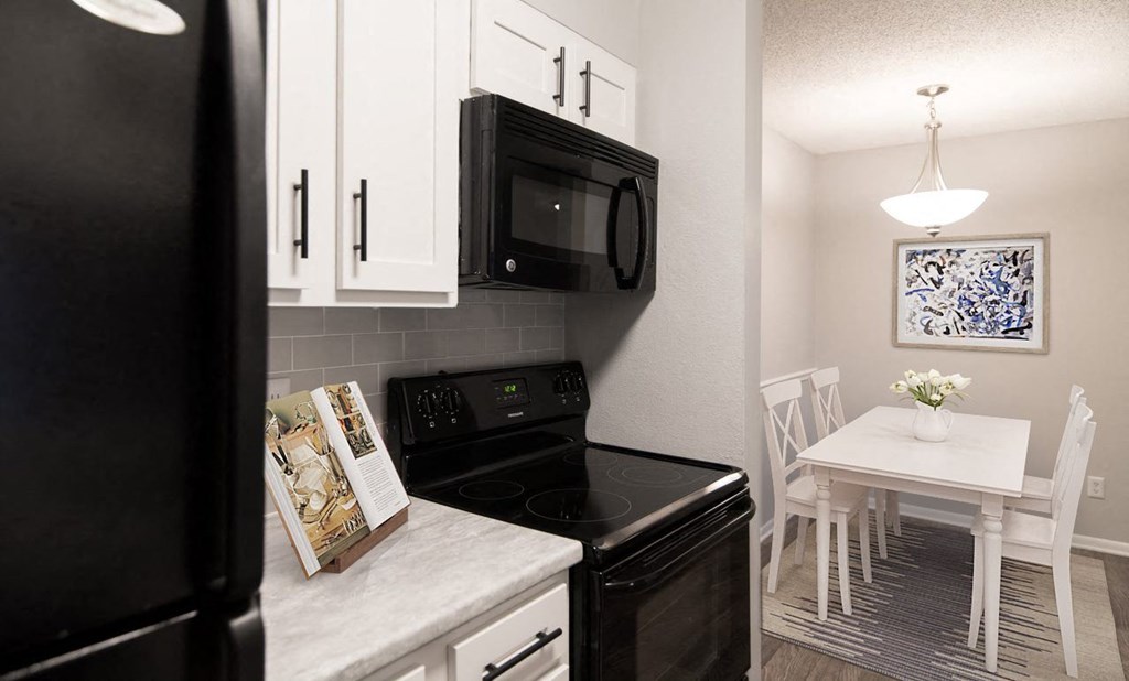 a kitchen with black appliances and a white dining room table