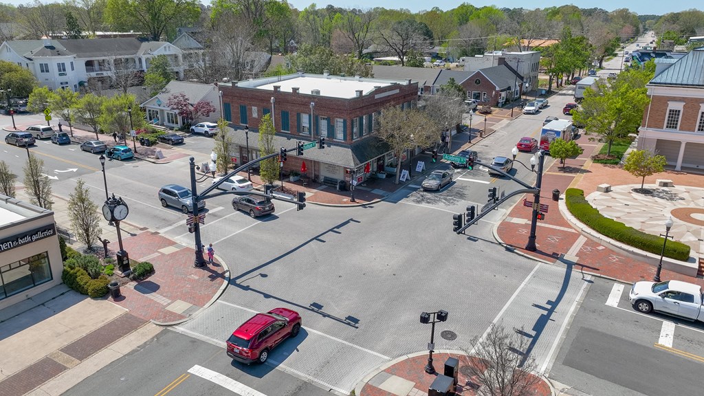 A red car is driving through a small town intersection.