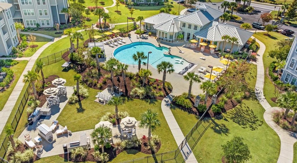 A large swimming pool surrounded by palm trees and a white building.